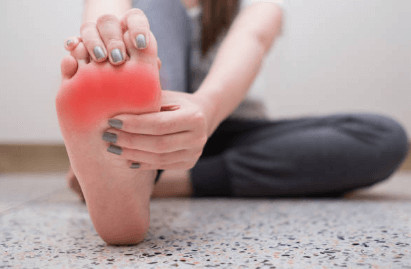 right foot showing red inflamed ball of foot, being gently stretched with right hand pulling toes back and left hand pressing mid foot