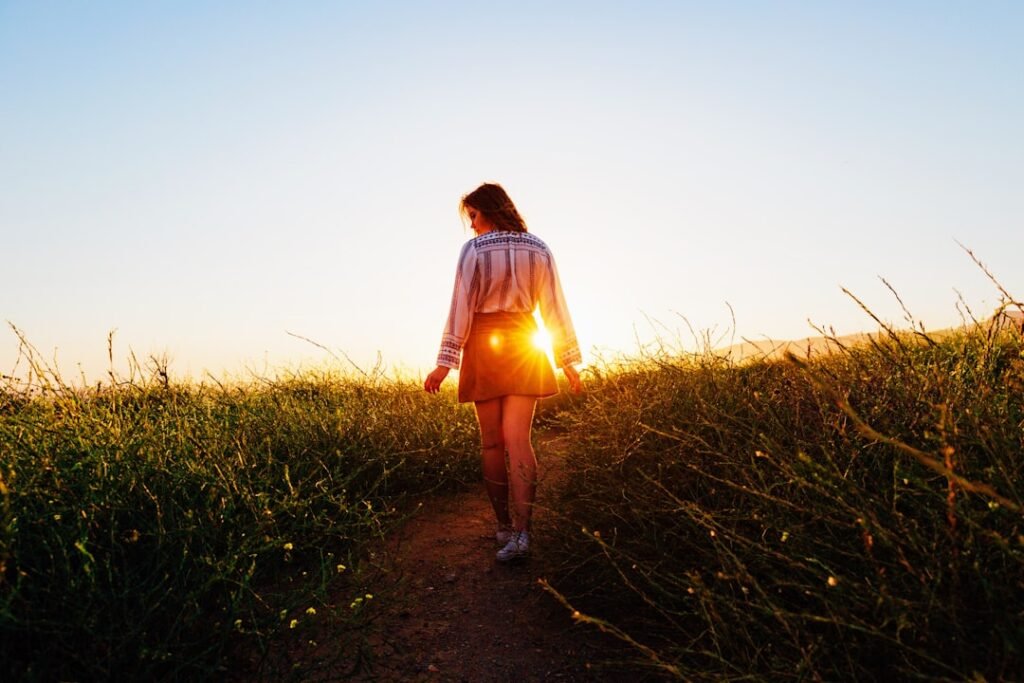 Woman walking barefoot on a sunlit pathway