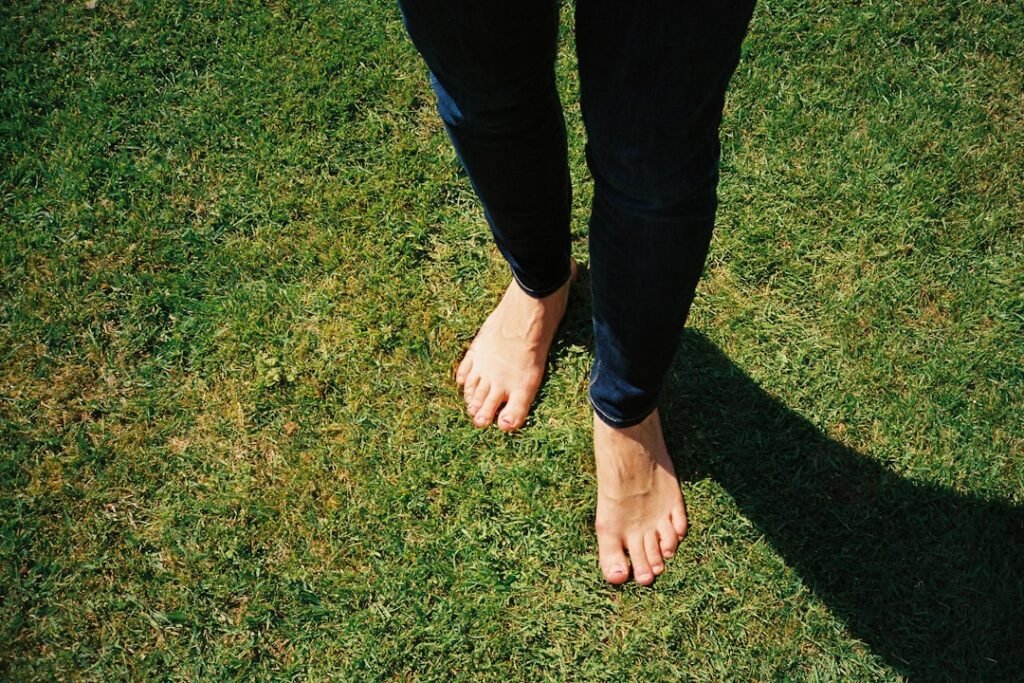 Bare feet standing on soft grass in warm sunlight