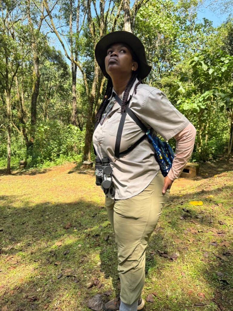Jane birding in the forest at Kapkwai, wearing a hat and binoculars, looking up into the trees. Last Birding Before Arachnoid Cyst Discovery