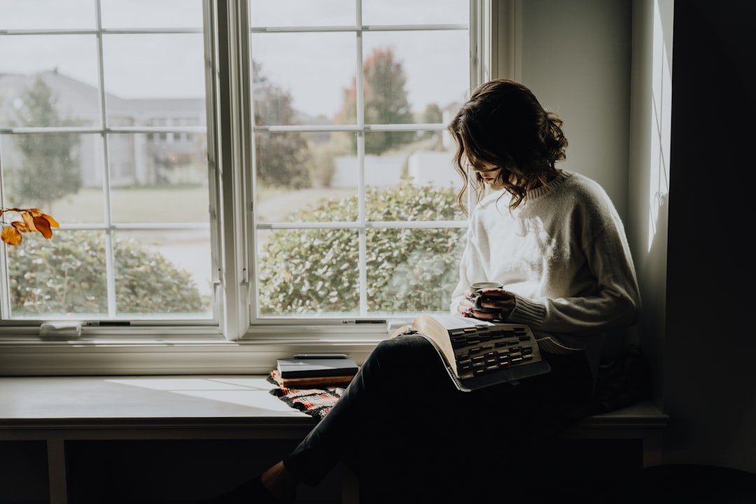 Woman reading by a sunlit window in a cozy warm room