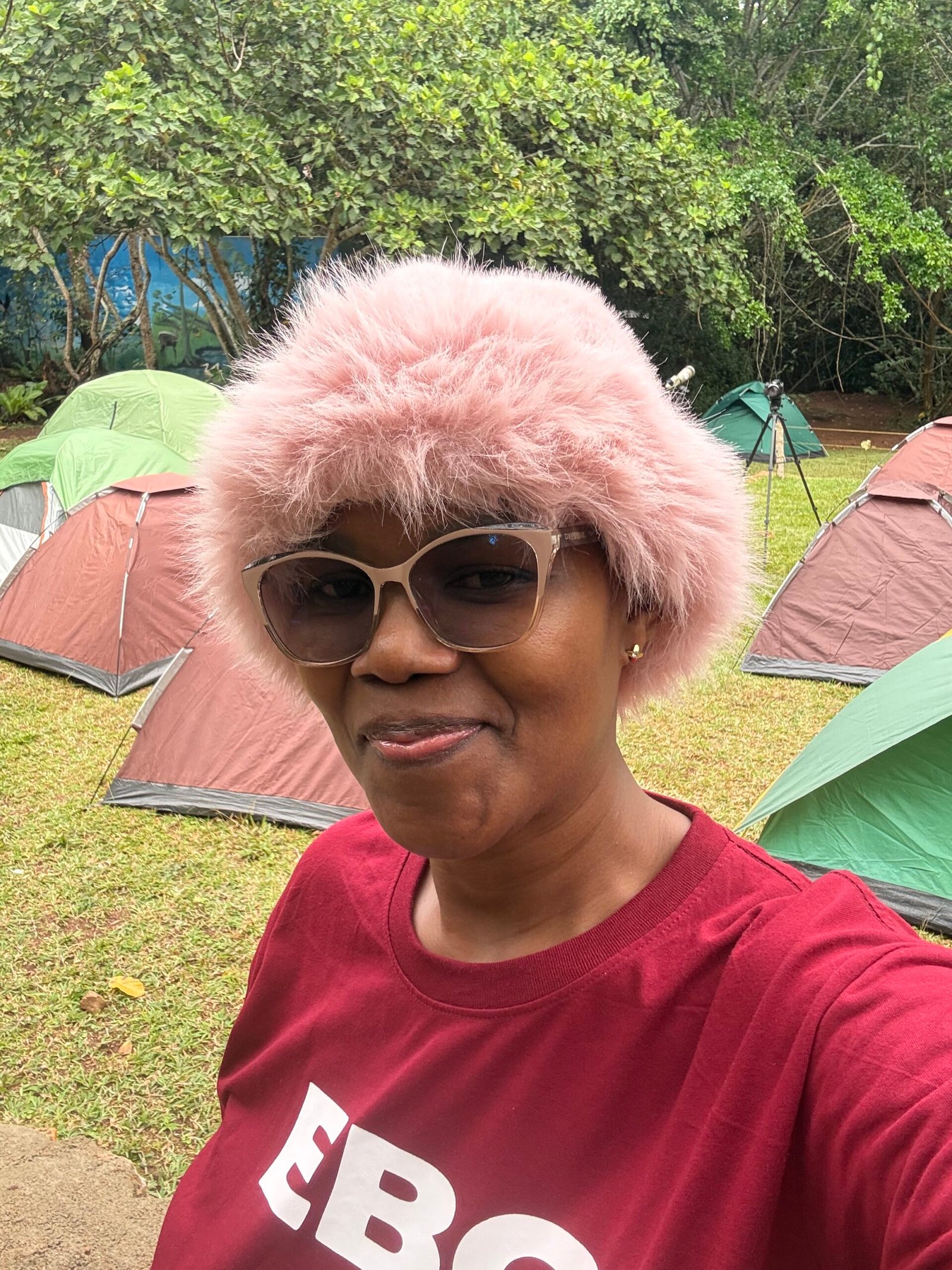 Smiling at a birding club camping trip, surrounded by tents and nature