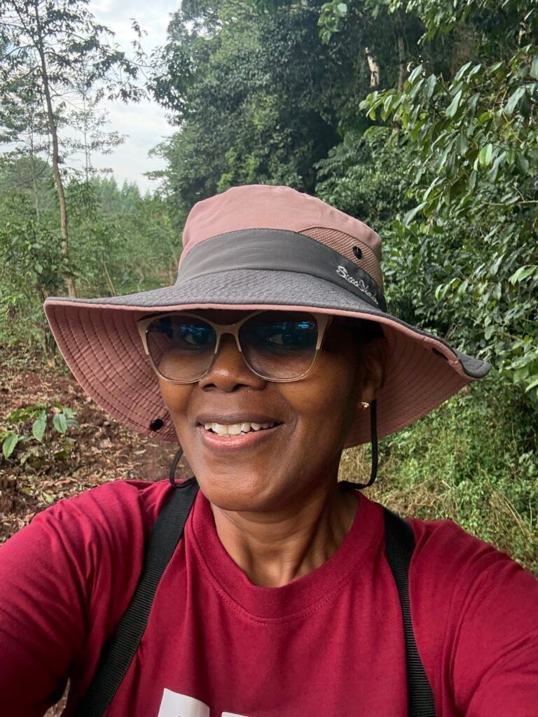 Woman smiling on a forest trail in a sun hat and sunglasses during a birding trip